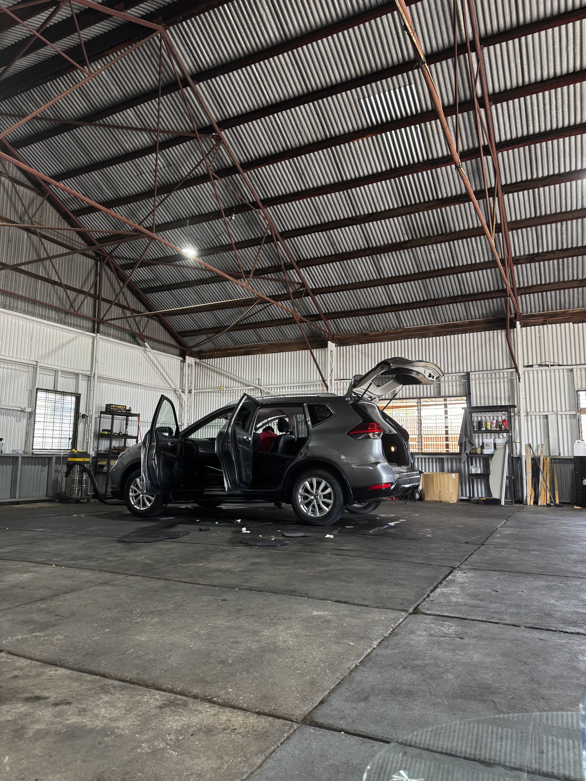 An SUV with every door open being vacuumed in the wash bay